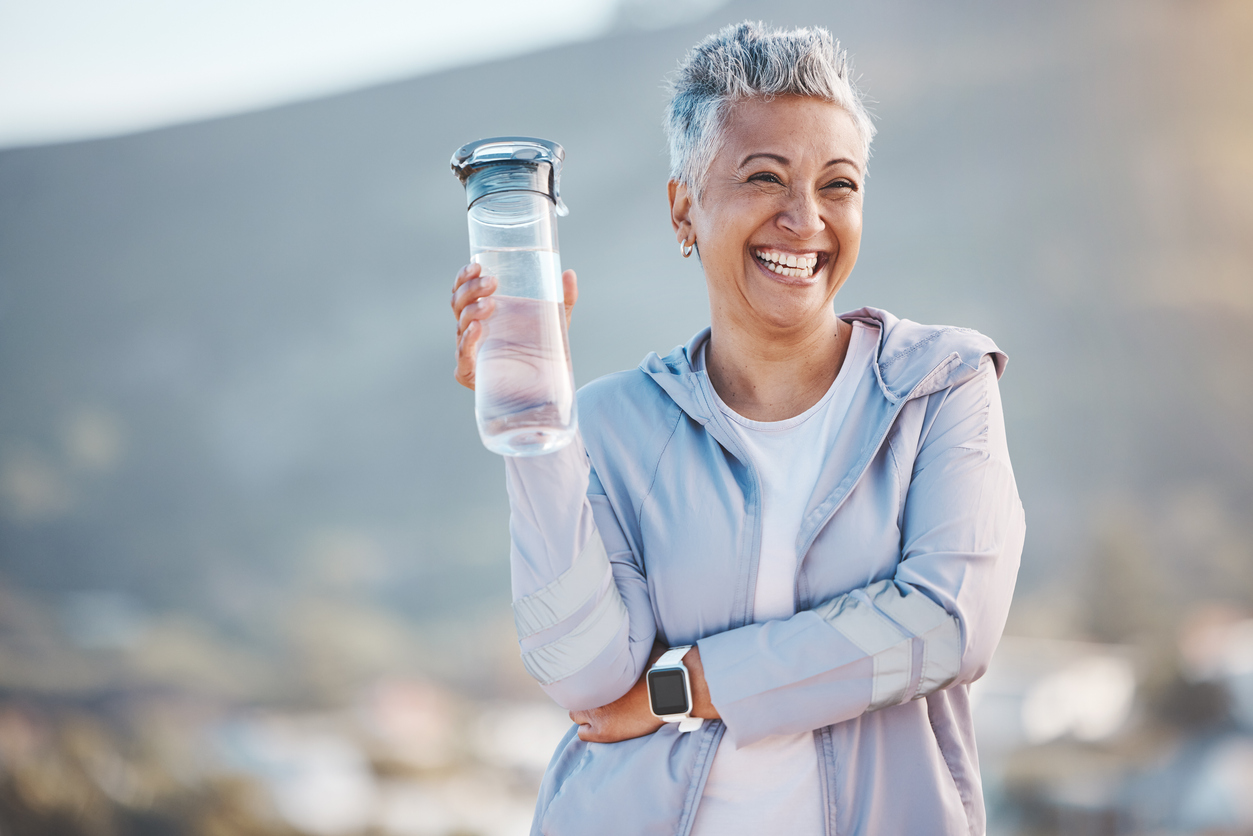 Smiling woman age 40+ in workout gear holding a water bottle reversing menopausal weight gain